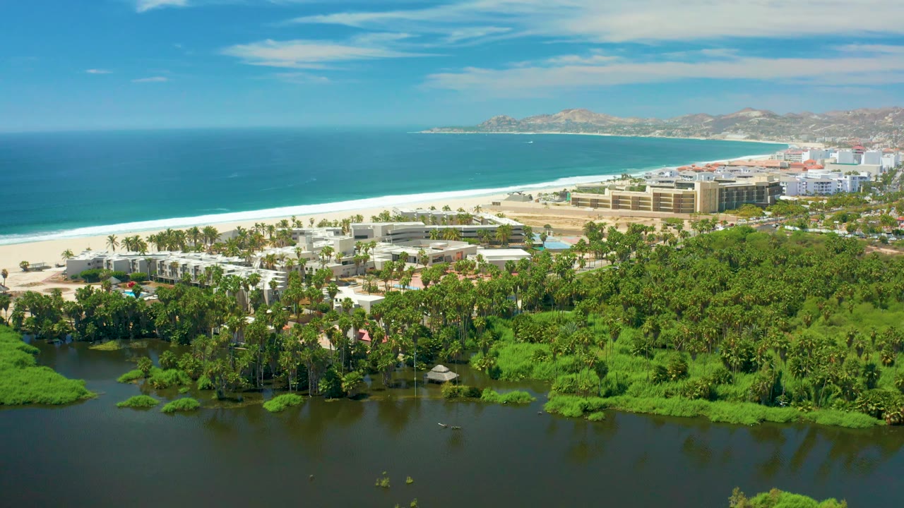 Aerial coastal view with lagoon water in front of beach hotels and ocean.