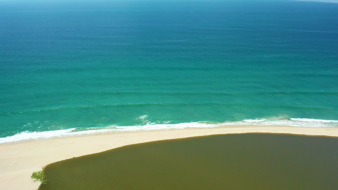 Aerial view of turquoise ocean meeting a pale sandy beach