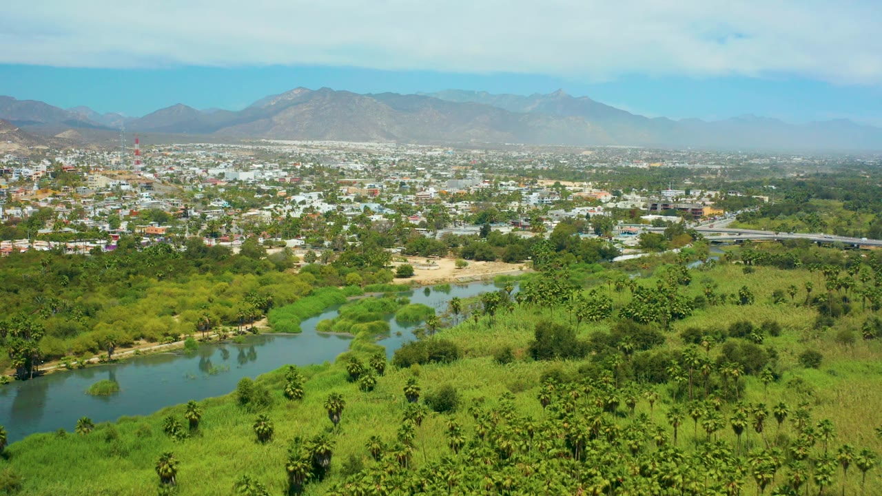 Town beside green fields with river in the foreground.