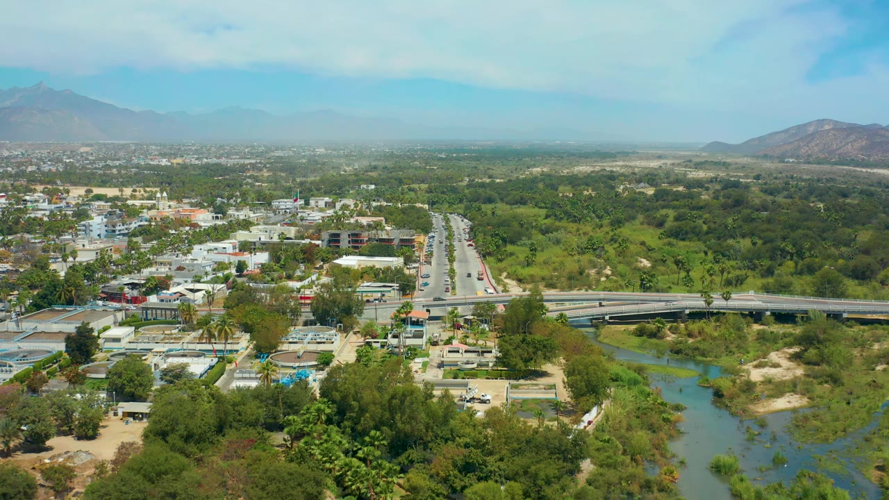 High aerial view of vehicles on a divided road beside a green river corridor.