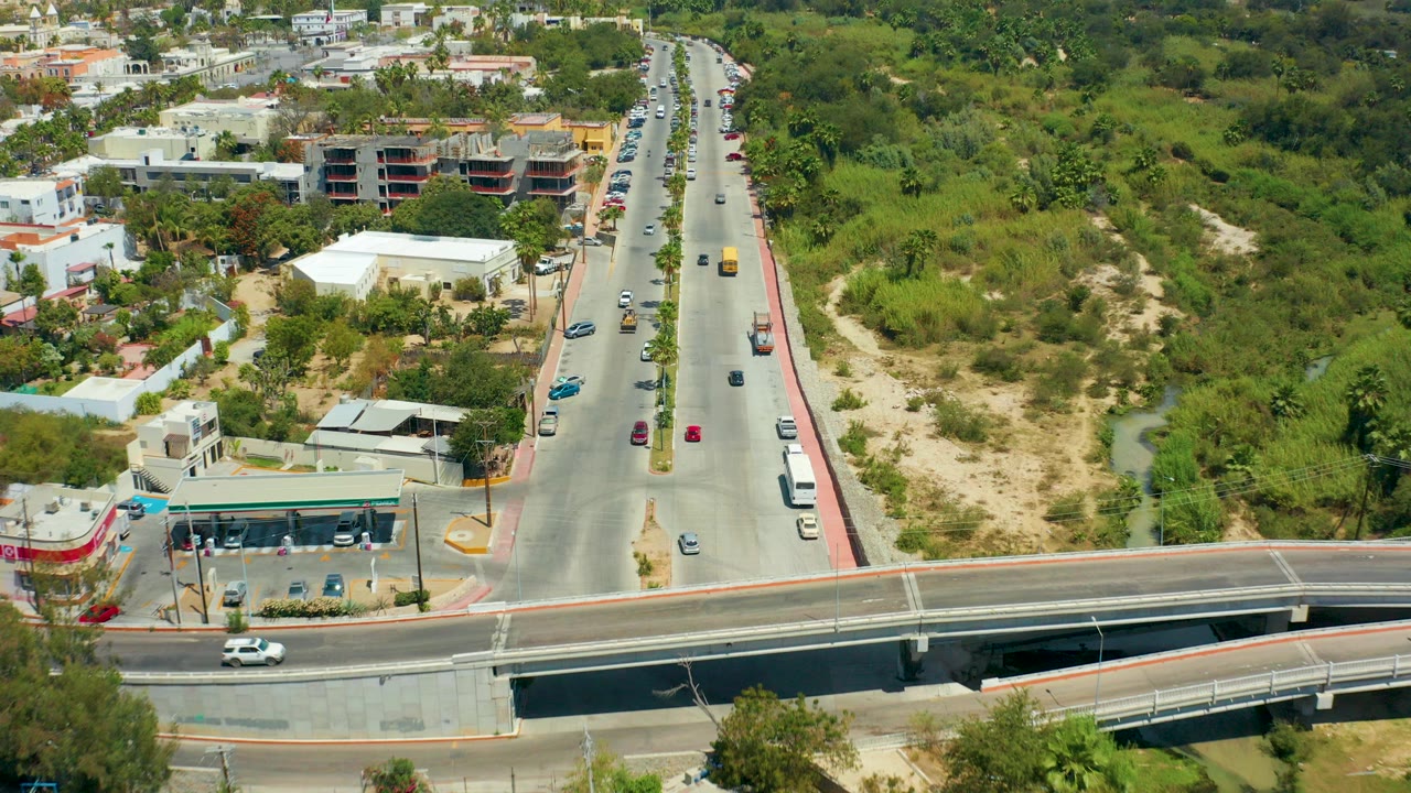 Aerial view of a road, overpass, cars, buildings, and green land.