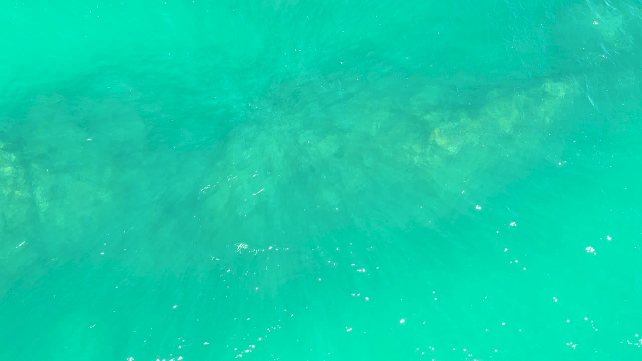 Turquoise water over a rocky seabed with small bubbles.