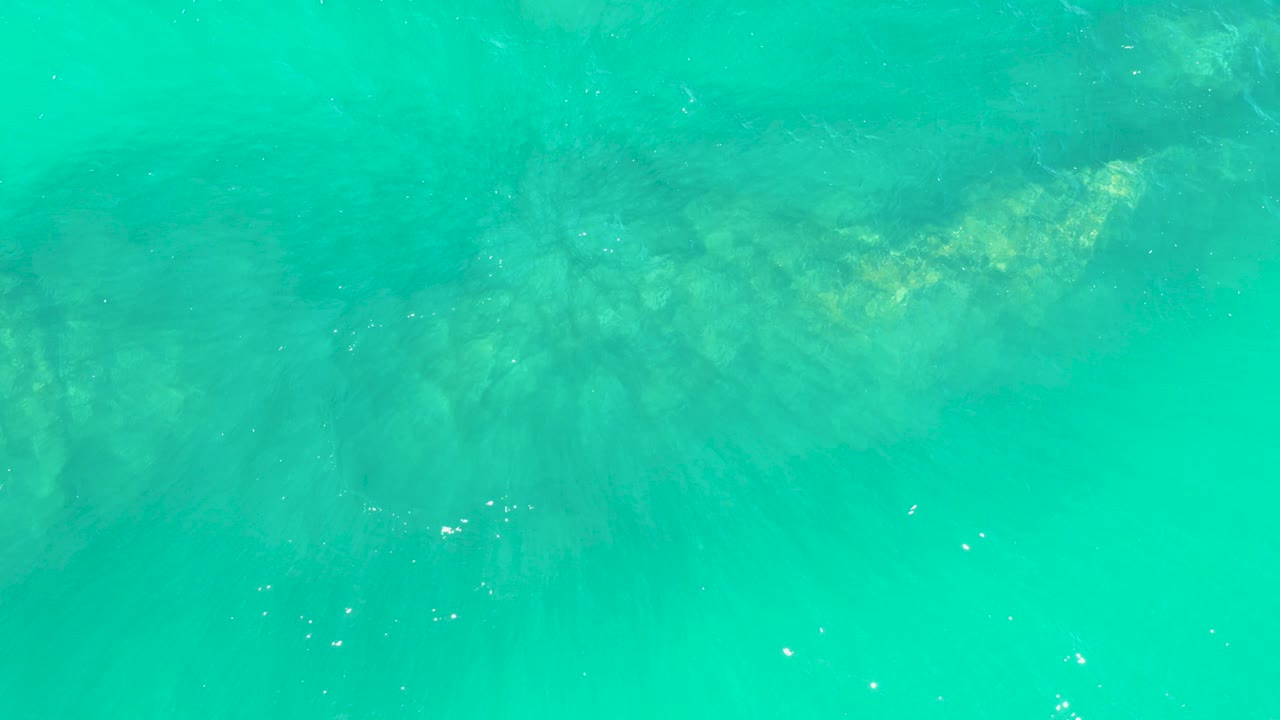 Turquoise water over a faint rocky seabed
