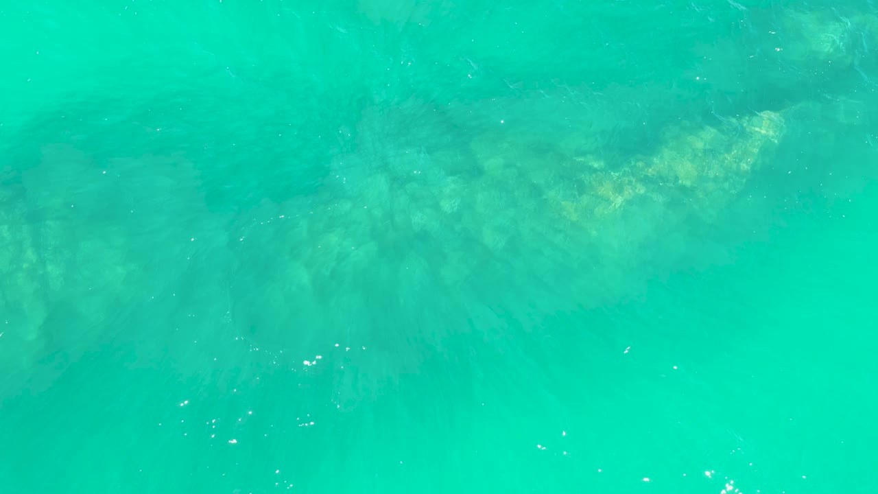 Sunlit patches on submerged rock appear through clear turquoise water at Marquis Los Cabos, with no visible people.
