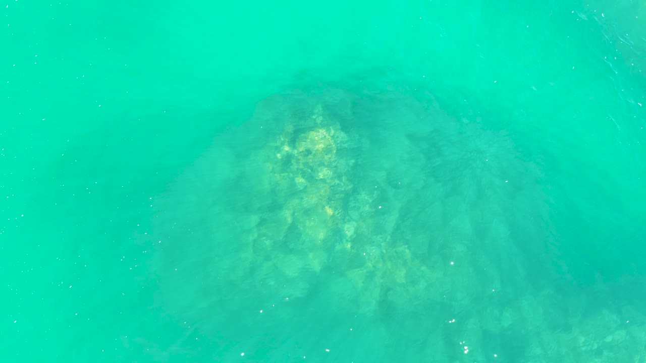 Large rock formation fading into turquoise underwater haze