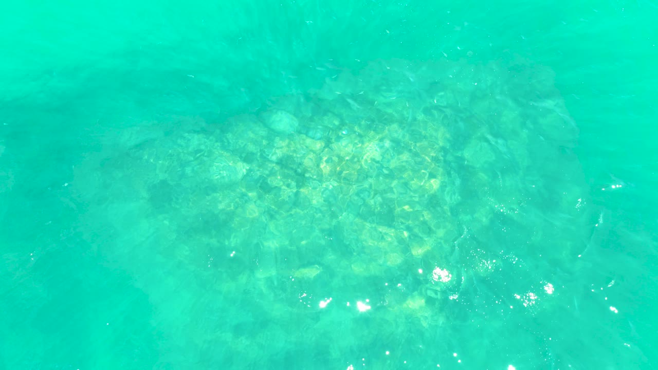 Clear turquoise water over a rocky seabed at Marquis Los Cabos, Baja California Sur, with soft sunlight patches and no visible people.