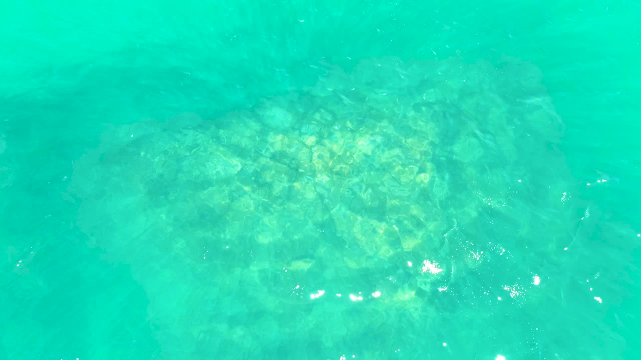 A slightly shifted view of clear water at Marquis Los Cabos shows the rocky ocean floor through turquoise surface ripples, with no visible people.
