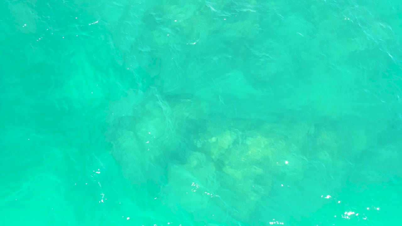 Clear aqua water with pale rocks visible beneath ripples.