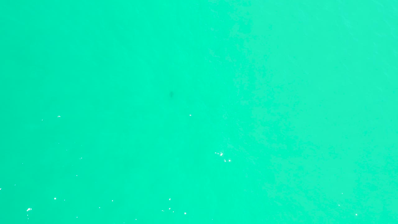 Bright turquoise ocean at Marquis Los Cabos with scattered white bubbles and no shoreline or visible people.