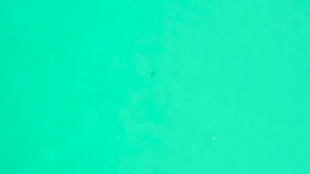 Clear teal ocean surface at Marquis Los Cabos, with soft ripple patterns, tiny bright specks on the water, and no visible people.