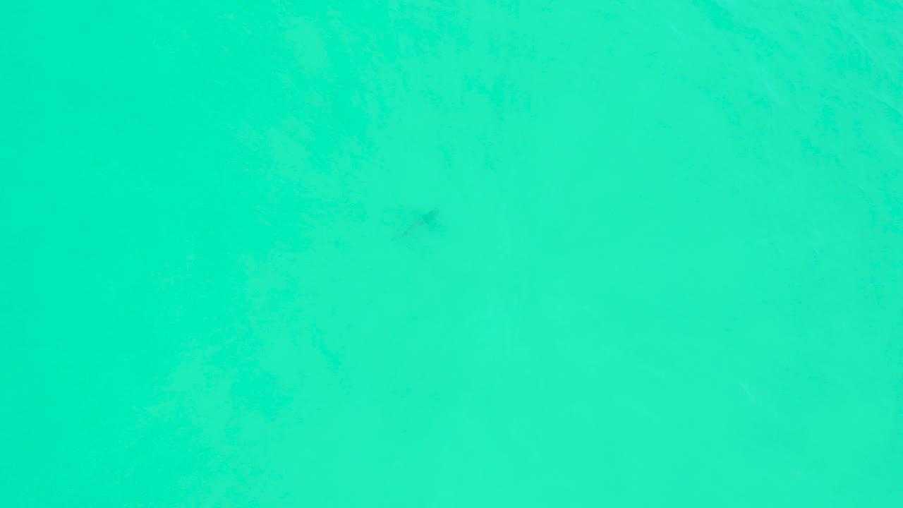 Overhead turquoise ocean water at Marquis Los Cabos shows soft darker patches beneath the surface and no visible people.