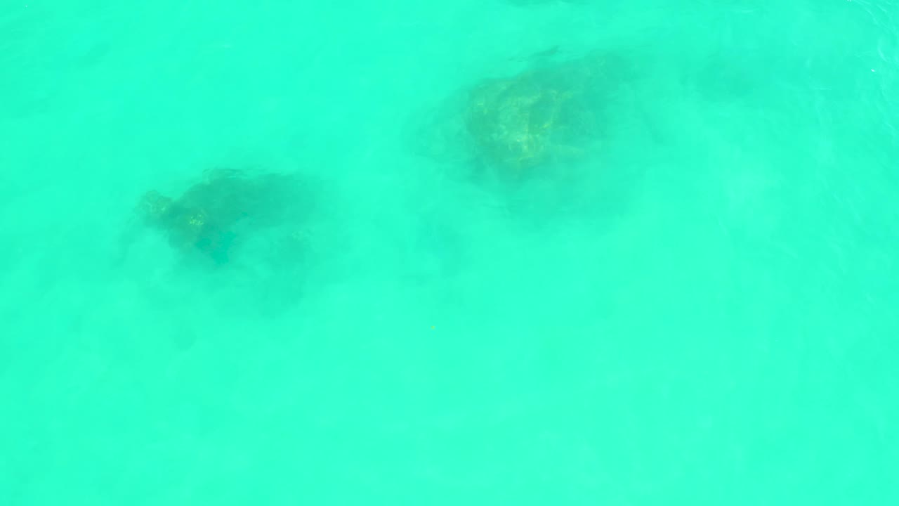 Bright turquoise water at Marquis Los Cabos shows dark underwater formations softened by surface motion, with no visible people.