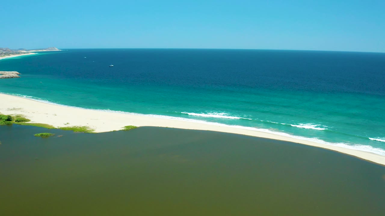 Aerial coastline with estuary foreground and turquoise waves beyond sand
