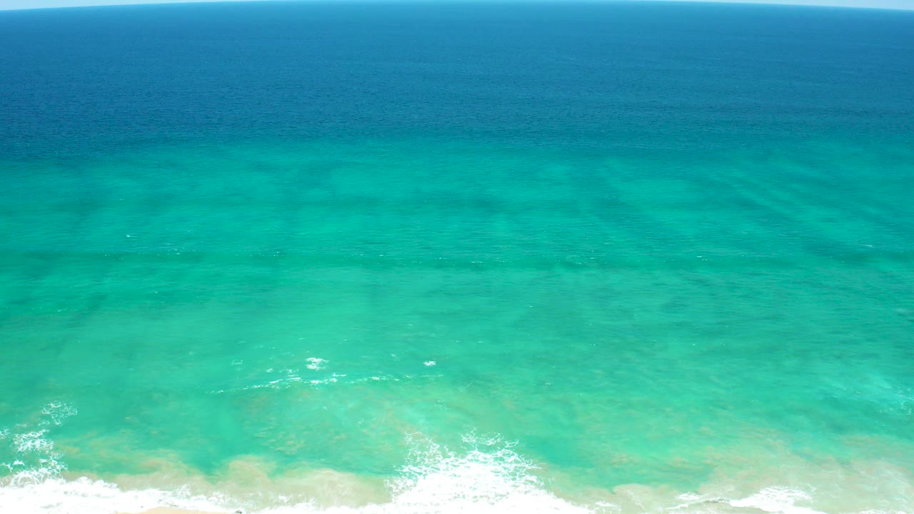 Turquoise ocean water with a thin white wave line near the shore.