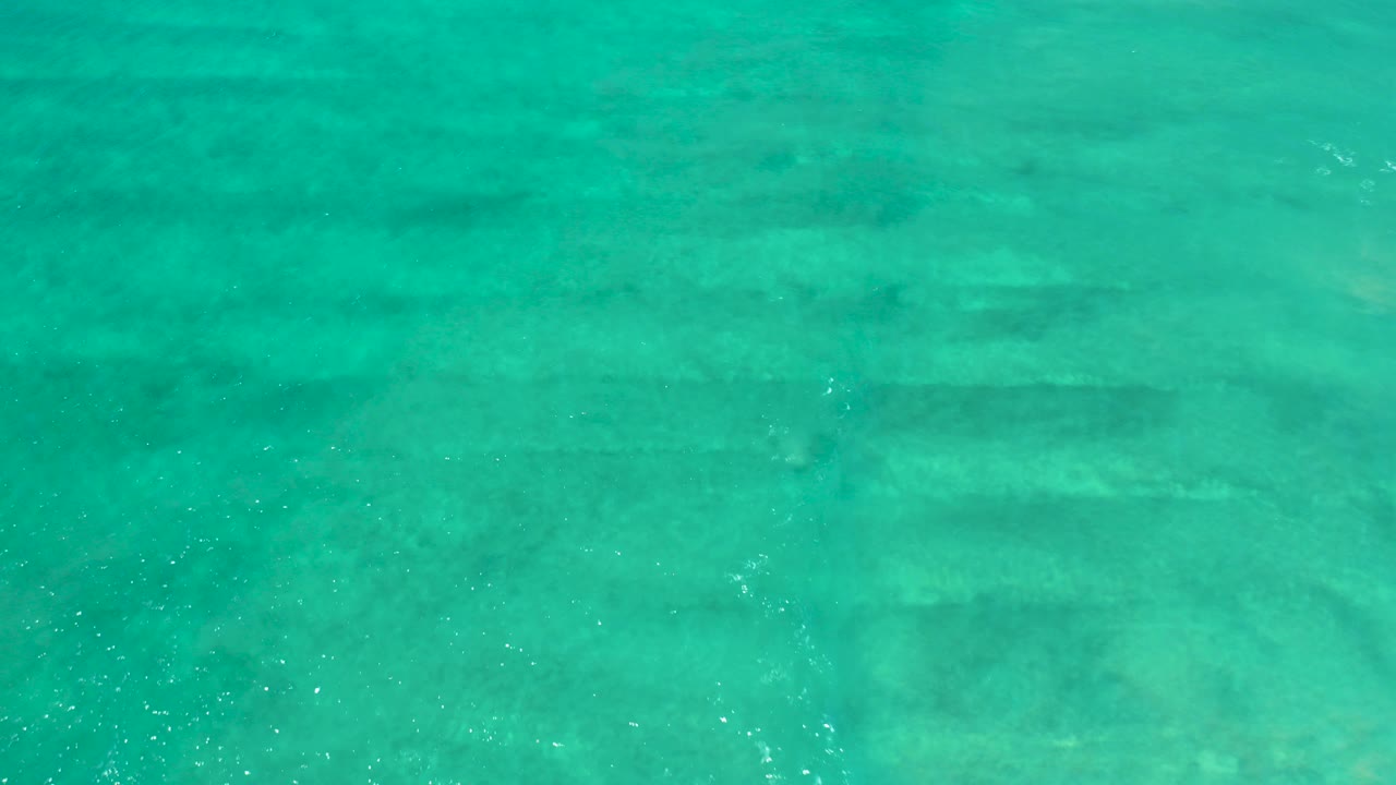 Clear turquoise water at San Jose Del Cabo Estuary with faint shallow bottom patterns, scattered light flecks, and no visible people.