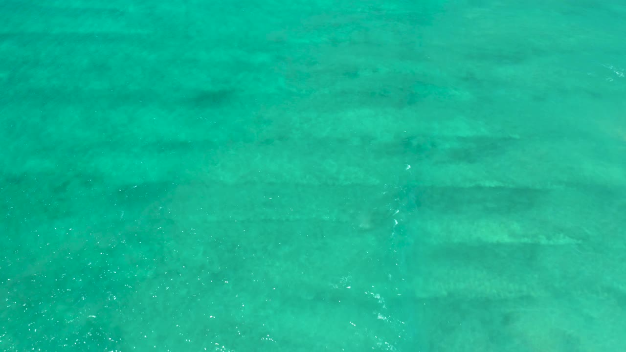 Turquoise water at San Jose Del Cabo Estuary with brighter specks of sunlight on the rippled surface and no visible people.