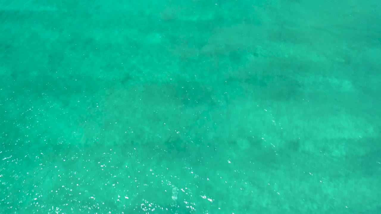 Clear turquoise water in San Jose del Cabo Estuary shows a slightly denser band of sunlight sparkles near the lower part of the frame, with no visible people.