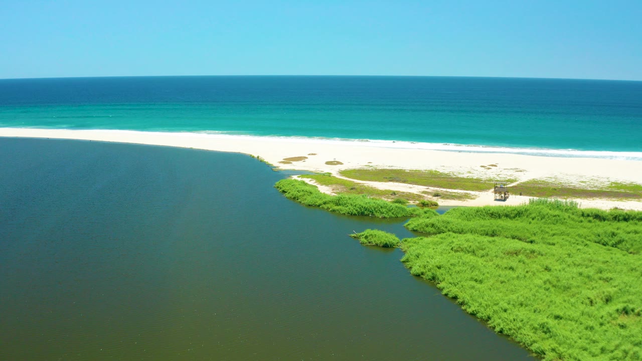 Aerial view of lagoon water, green vegetation, white sand beach, and turquoise ocean
