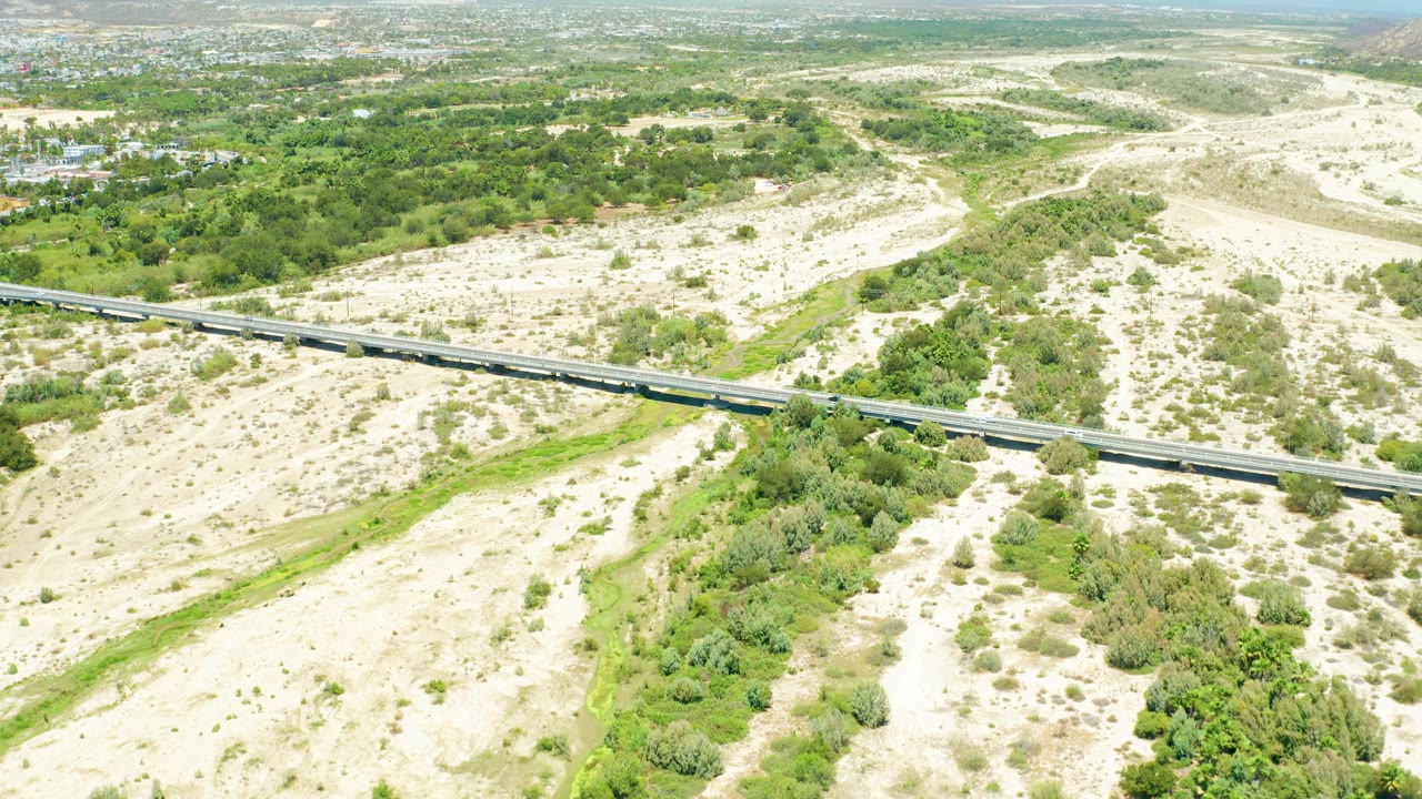 Aerial landscape with a train bridge crossing sandy ground and greenery.