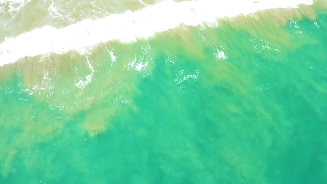 Overhead turquoise water with a white foamy wave at the top edge.