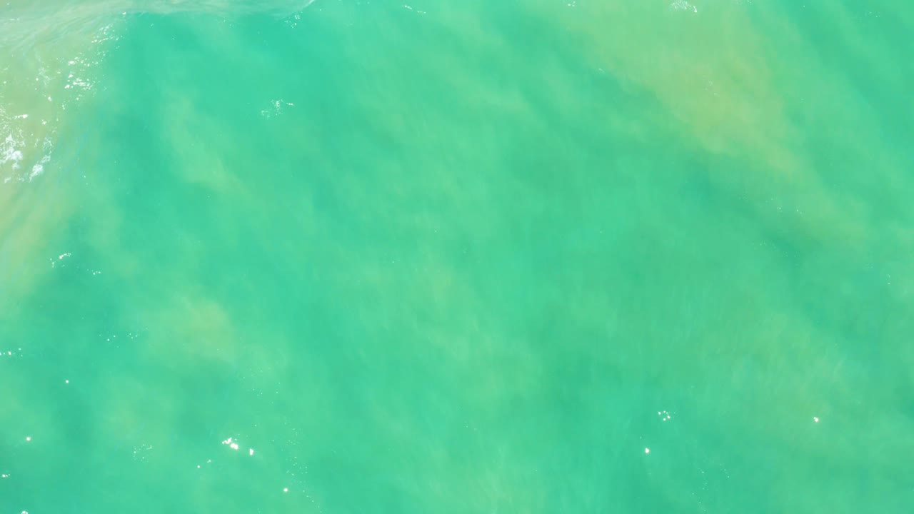 Turquoise and green water at San Jose Del Cabo Estuary shows cloudy pale seabed patches beneath light ripples, with no visible people or objects.