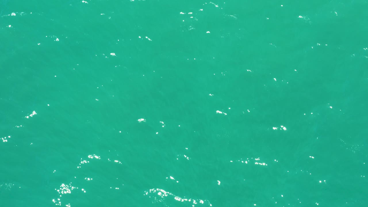 Turquoise ocean surface with small white light reflections.