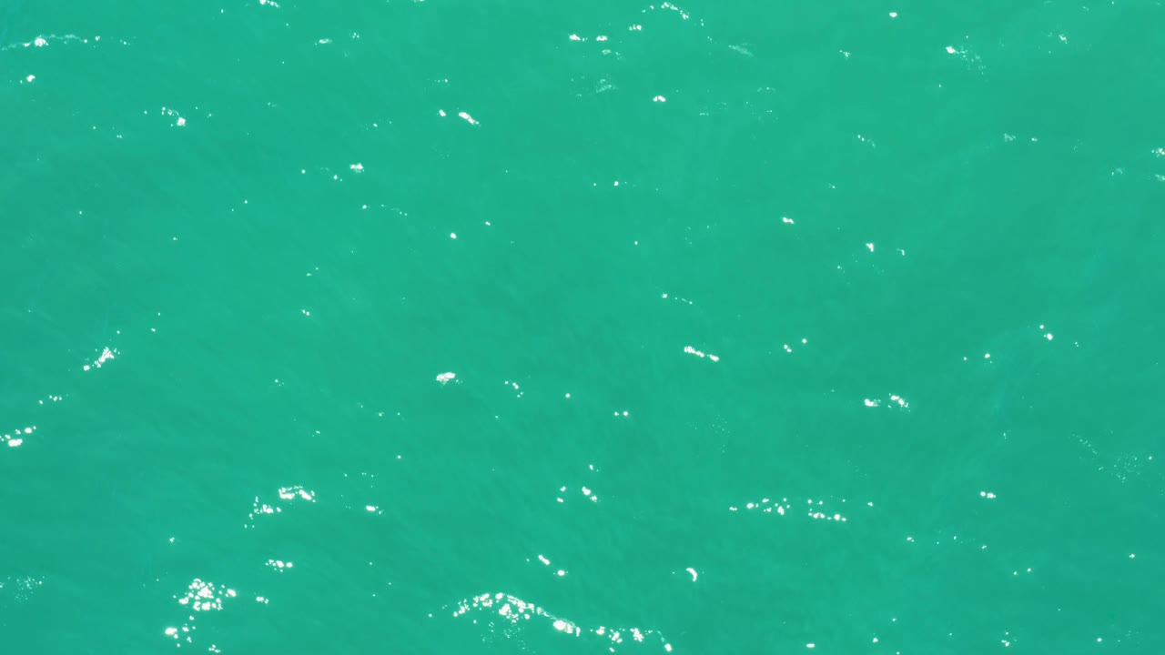 A teal section of ocean surface at San Jose Del Cabo Estuary shows scattered bright glints across small ripples, with no visible people or objects.