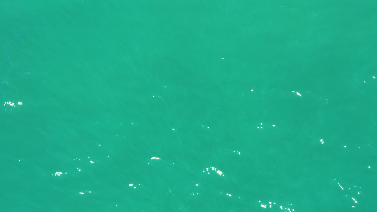 Turquoise water at San Jose Del Cabo Estuary shows faint wave patterns and sparse white reflections across an uninterrupted surface, with no visible people.