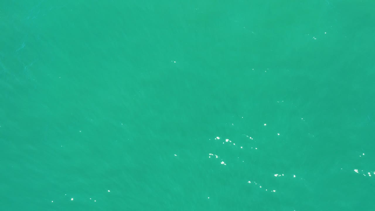 Turquoise water surface with small ripples and white light glints.