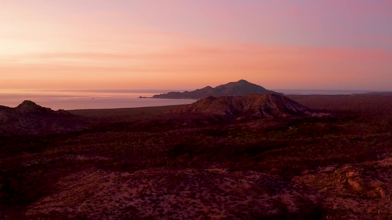 Desert foreground with mountain coastline and sunset ocean
