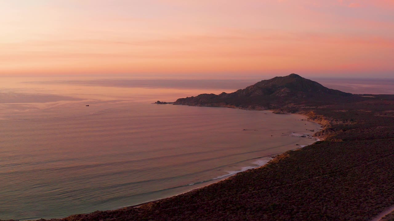 Aerial view of ocean, beach, hillside, and sunset sky