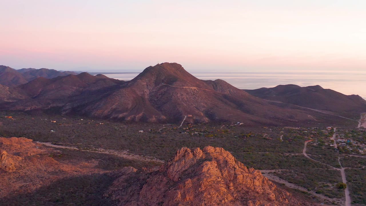 Drone view of rocky desert foreground, valley roads, and mountain slopes.