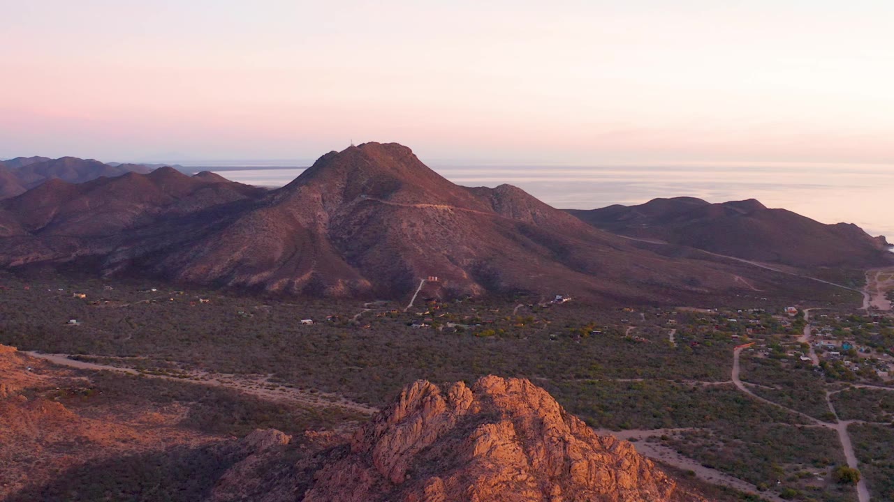 Central mountain and scrub valley under a pink sunset sky.