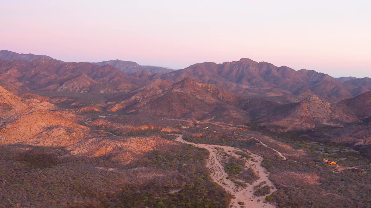 Winding desert road and ridges seen from above in warm dusk light.