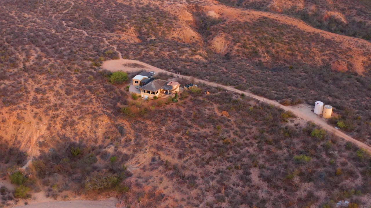 Aerial desert terrain with small house and service road