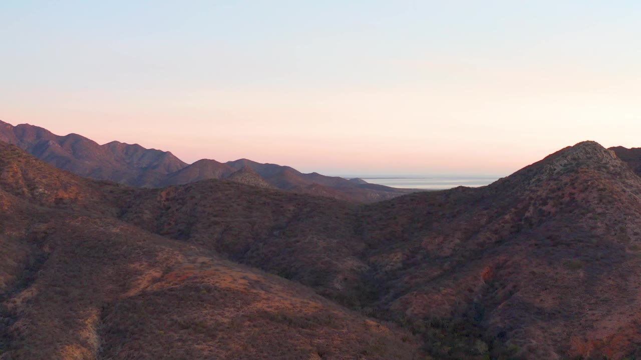 A broad Cabo Pulmo ridge line sits under soft sunset color, with warm highlights on rocky slopes and no visible people.