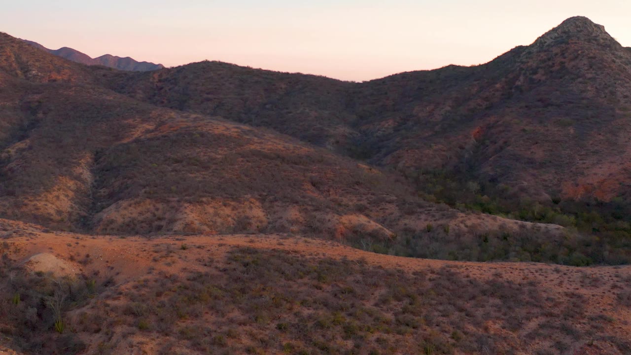 Mountain ridges and dry foreground under soft dawn or dusk light.