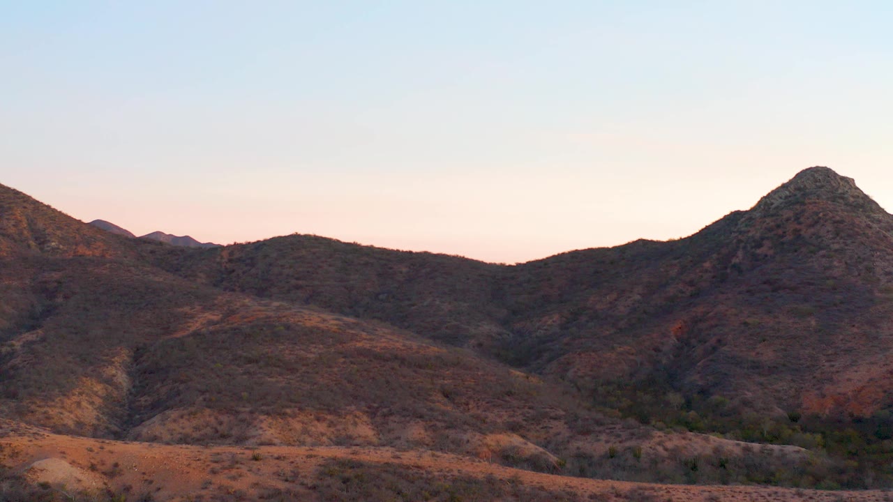 Rocky desert hills below a pale dusk sky.