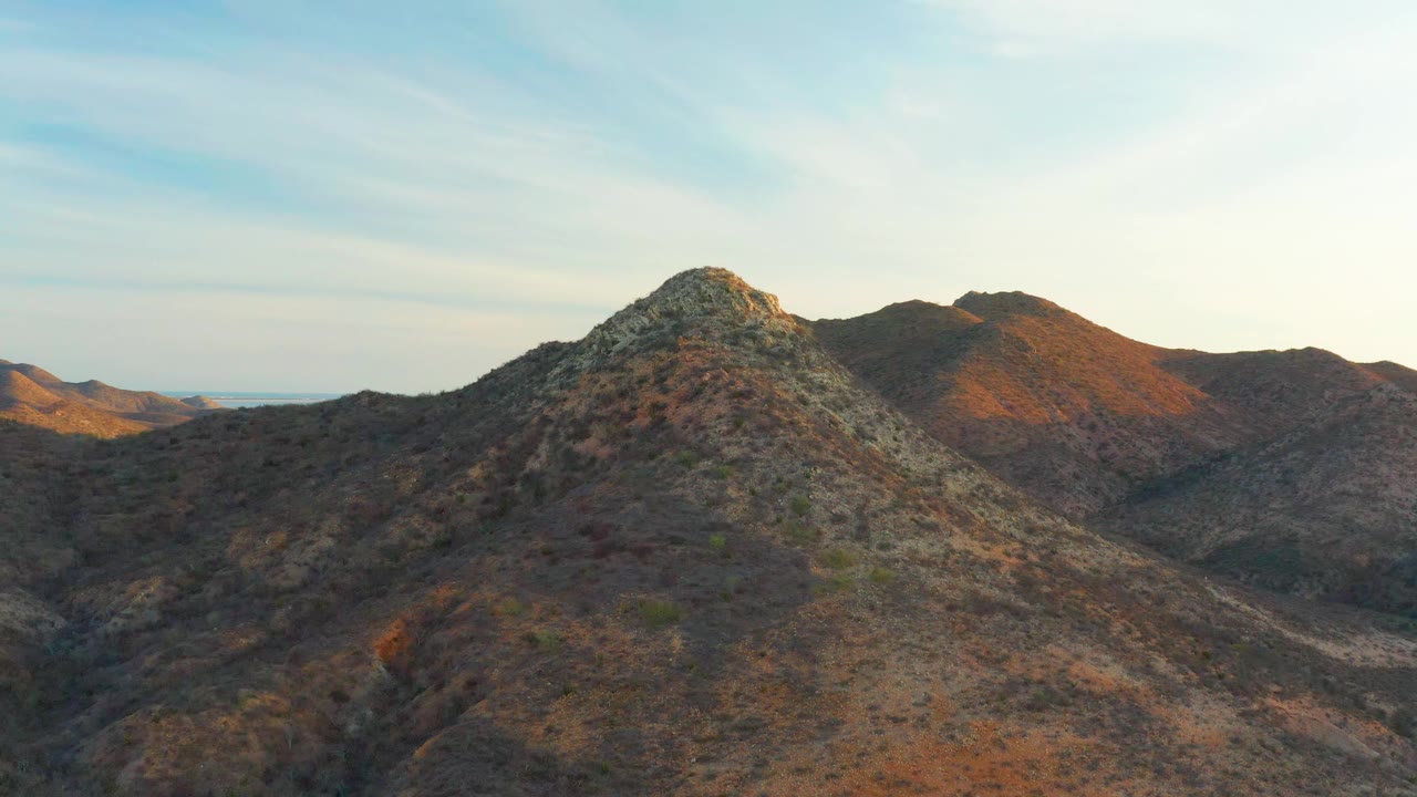 Cabo Pulmo mountain terrain with the central rocky peak slightly more centered, orange light catching the rear ridge, and no visible people.