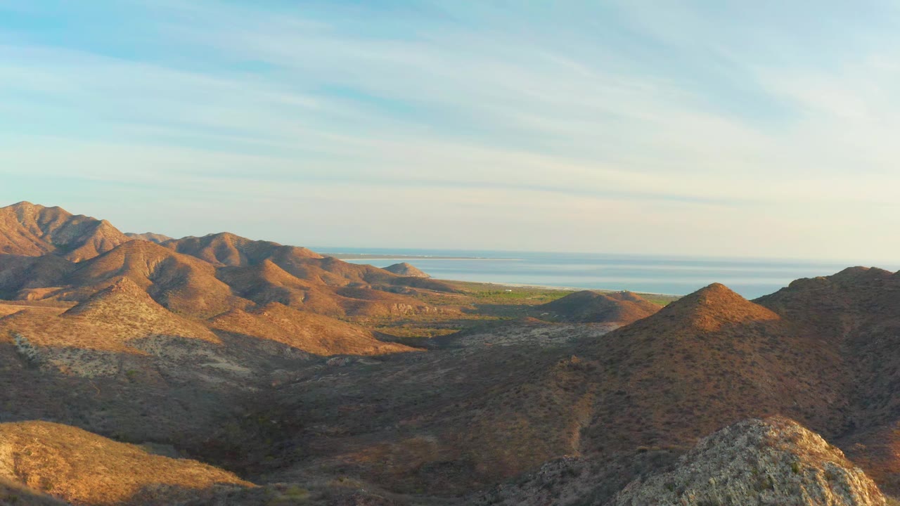 Cabo Pulmo mountain ridges remain spread across the frame, with the ocean visible behind the low valley and no visible people.