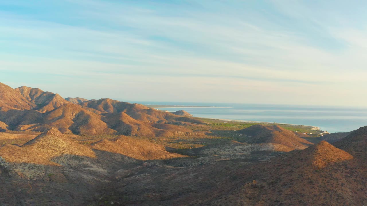 Sunlit desert hills with distant ocean and coastline