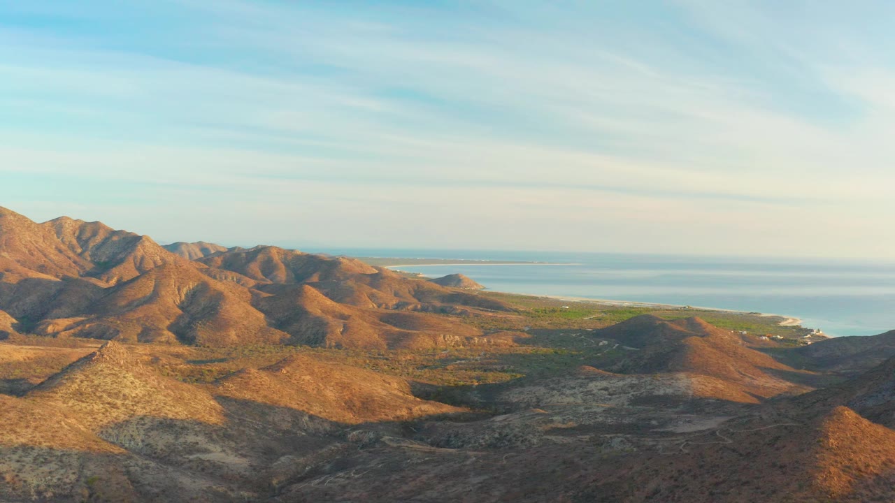 Desert hills and coastline under a pale blue sky.
