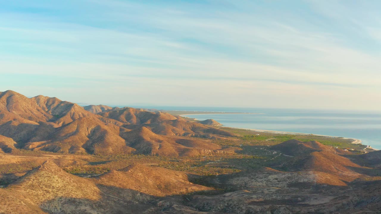 Coastal mountain ridges with broad sky and distant ocean.