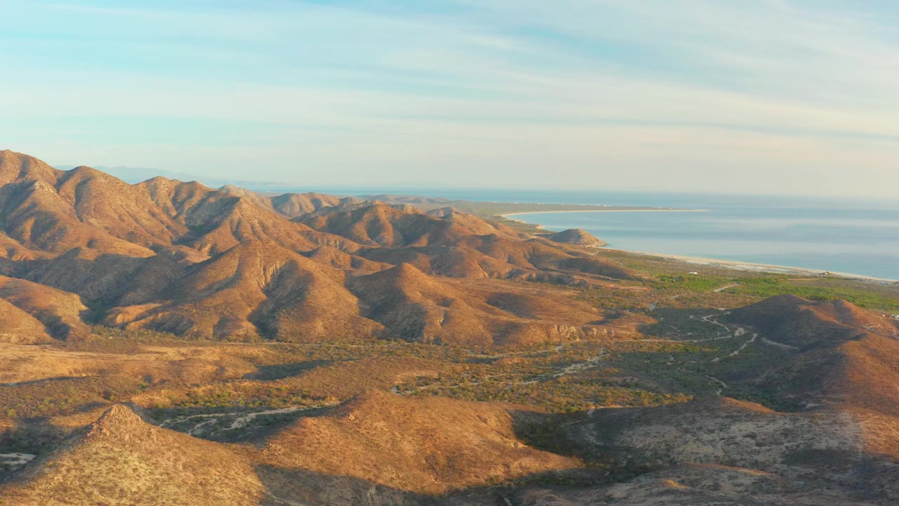 Dry mountain valley with sea behind the ridges.