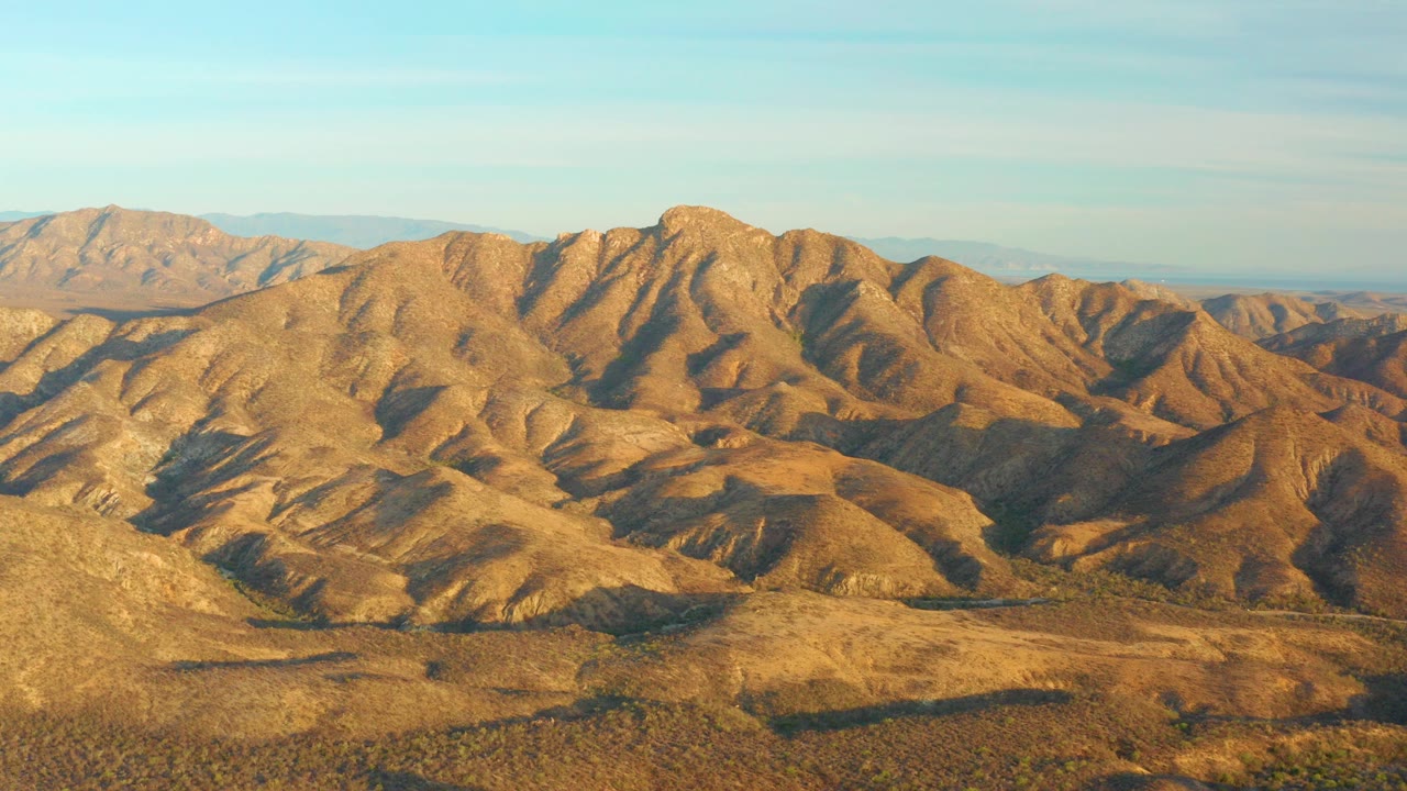 Golden desert hills under a pale blue sky