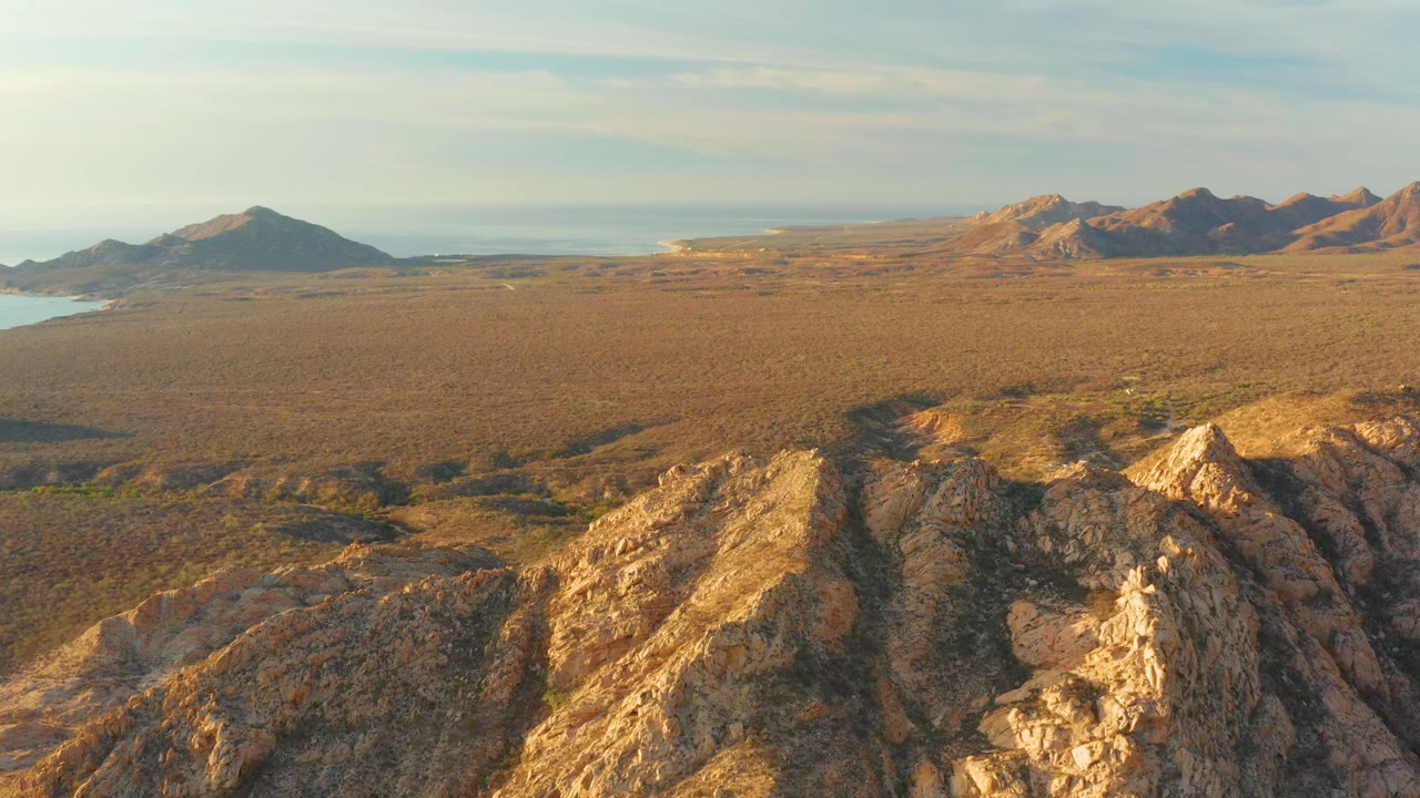 Wide arid valley seen from above rocky desert hills.