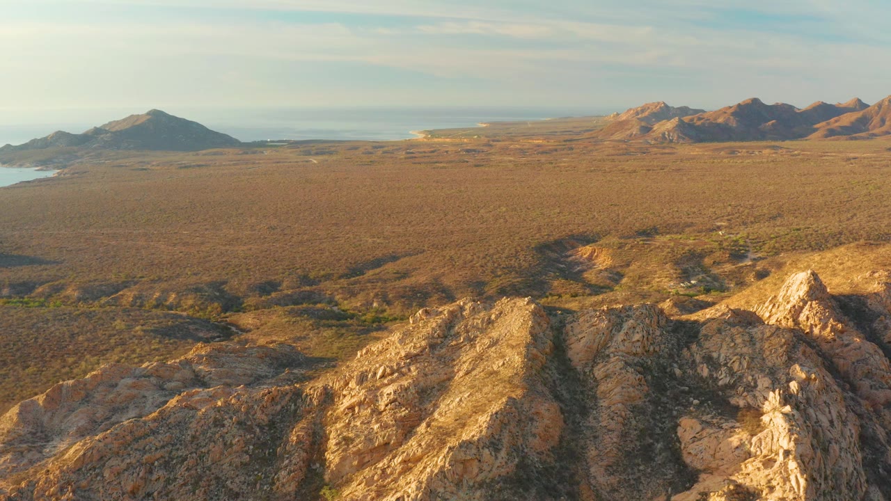 Rocky slope in foreground with open plain and distant mountains