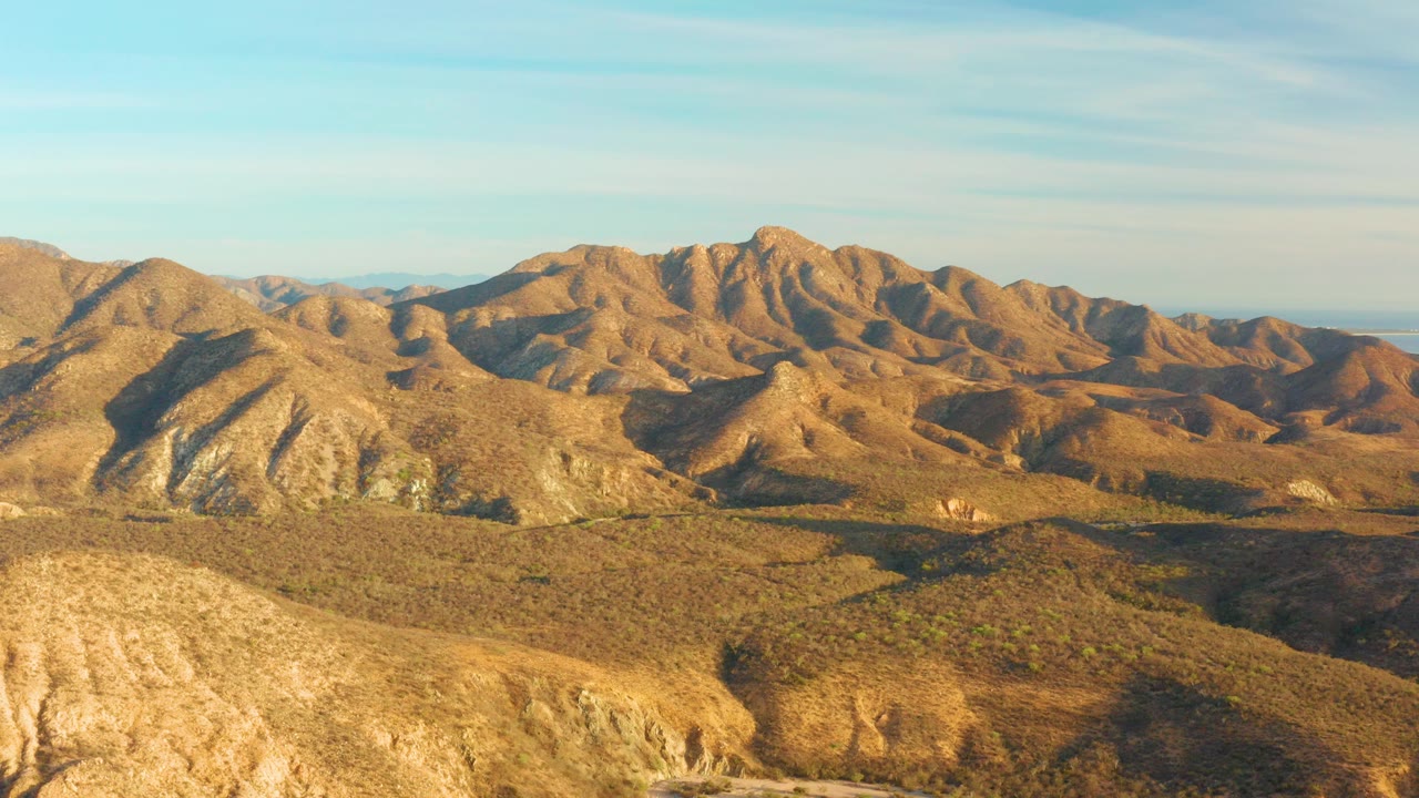 Wide desert hills and mountains under a blue sky.