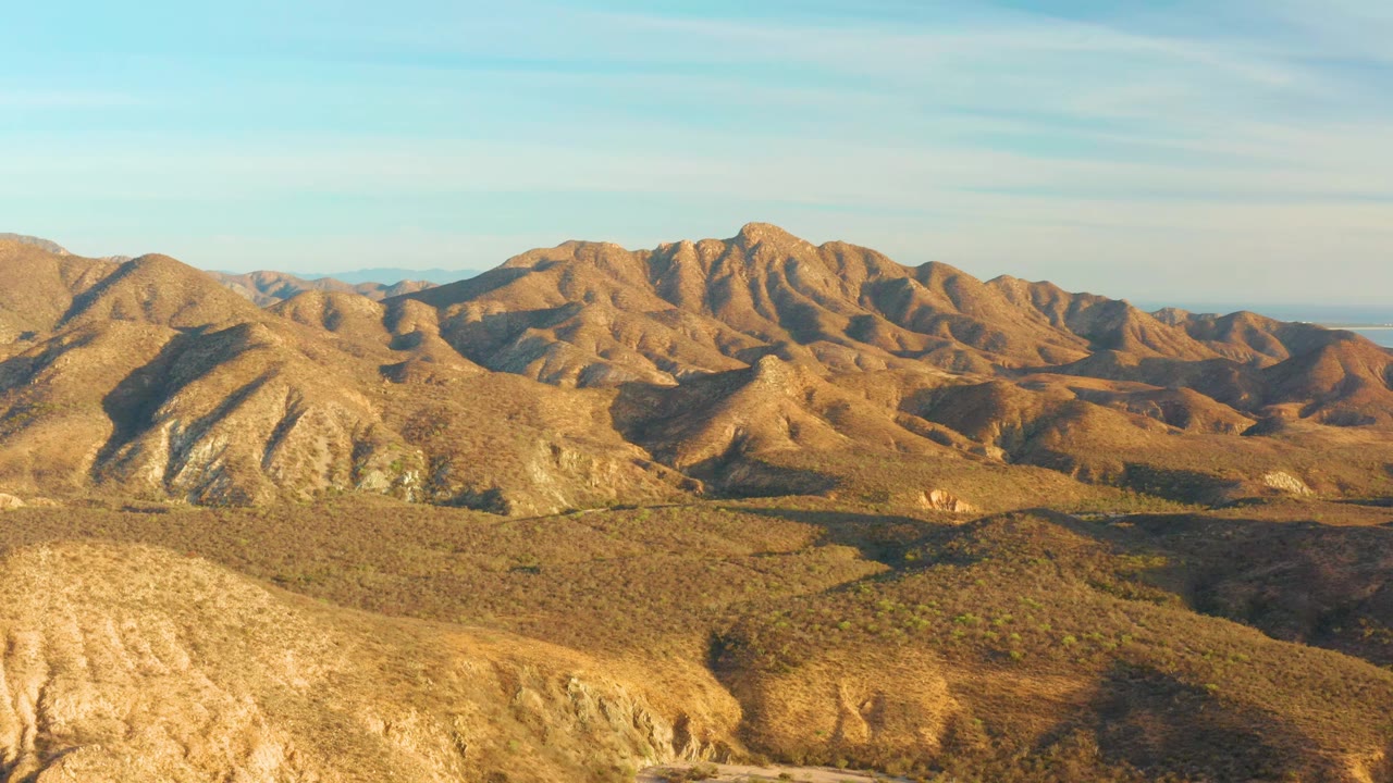 Sunlit arid slopes and a broad mountain ridge in Cabo Pulmo, Baja California Sur, Mexico, with the foreground hill crossing the lower frame and no visible people.