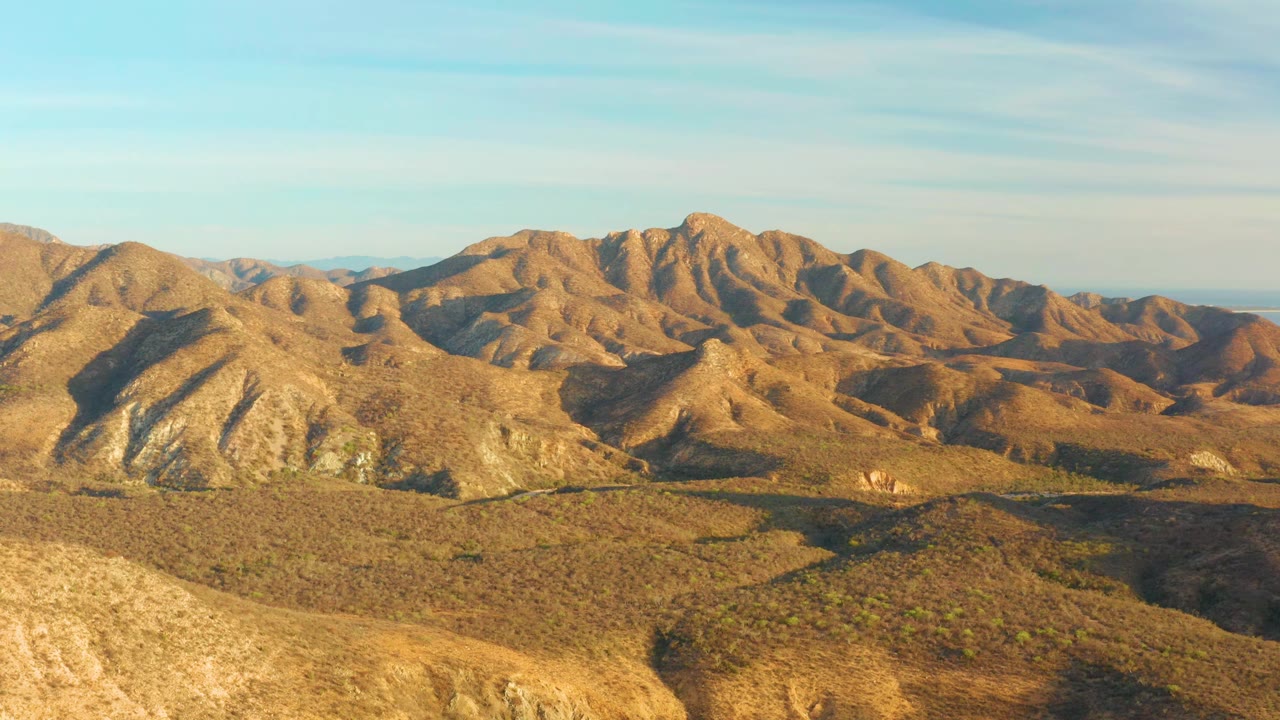 At 0:01, the Cabo Pulmo desert mountains remain framed wide, with shadowed gullies cutting through sunlit brown slopes and no visible people.